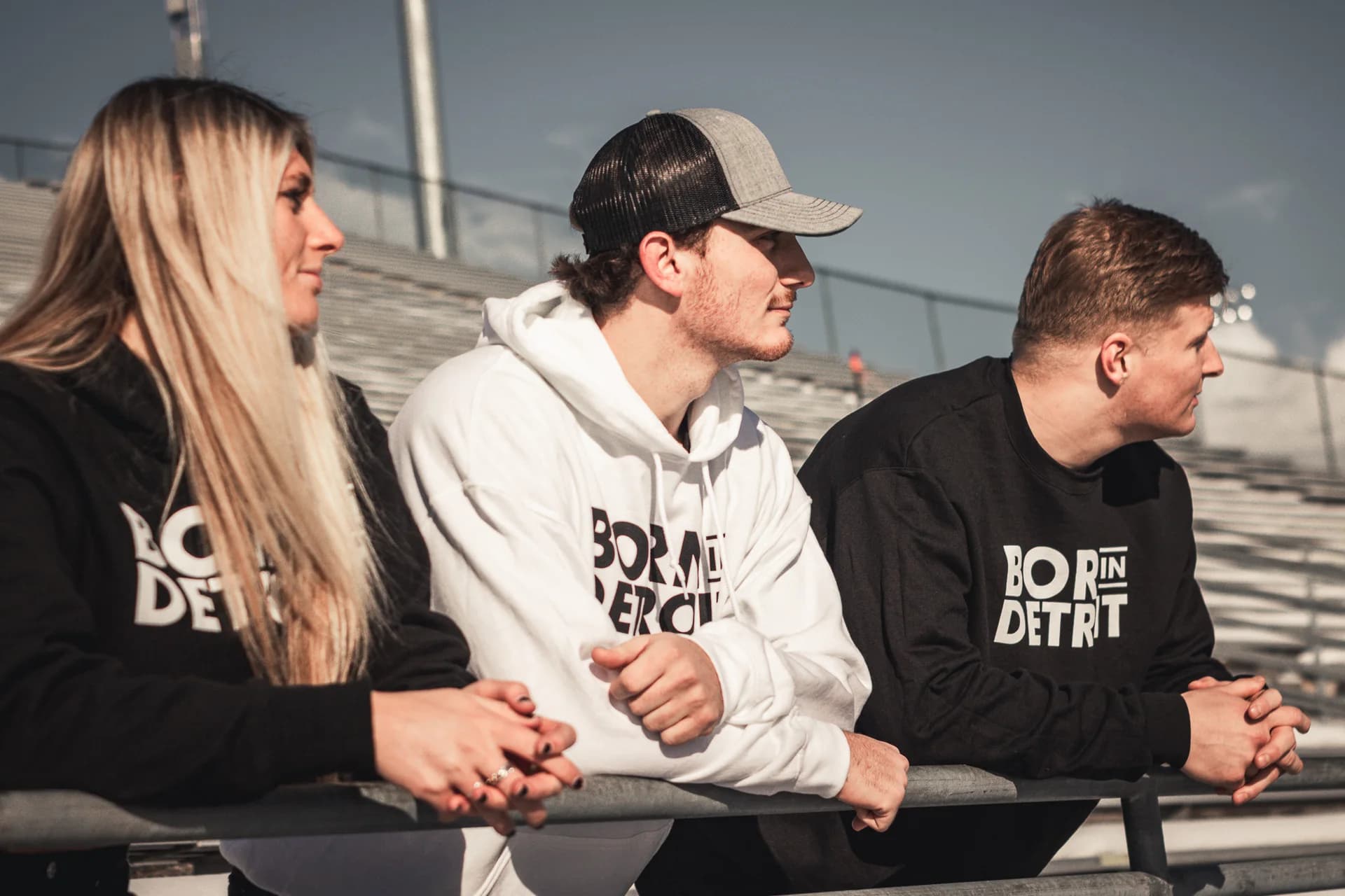 Three models wearing Born in Detroit sweatshirts on outdoor bleachers