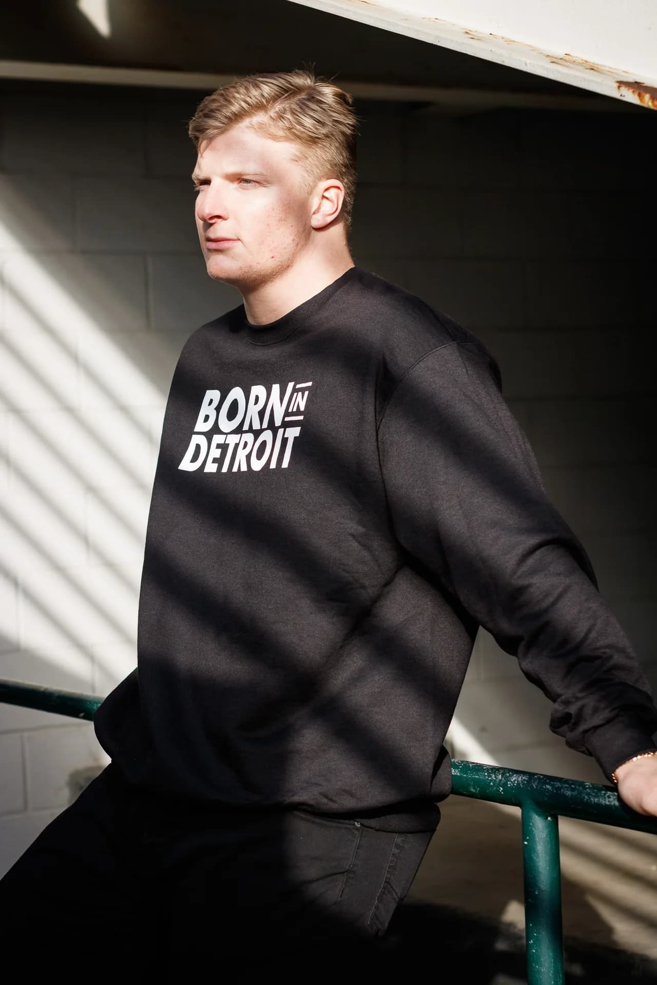 Model wearing a black Born in Detroit sweatshirt in directional sunlight