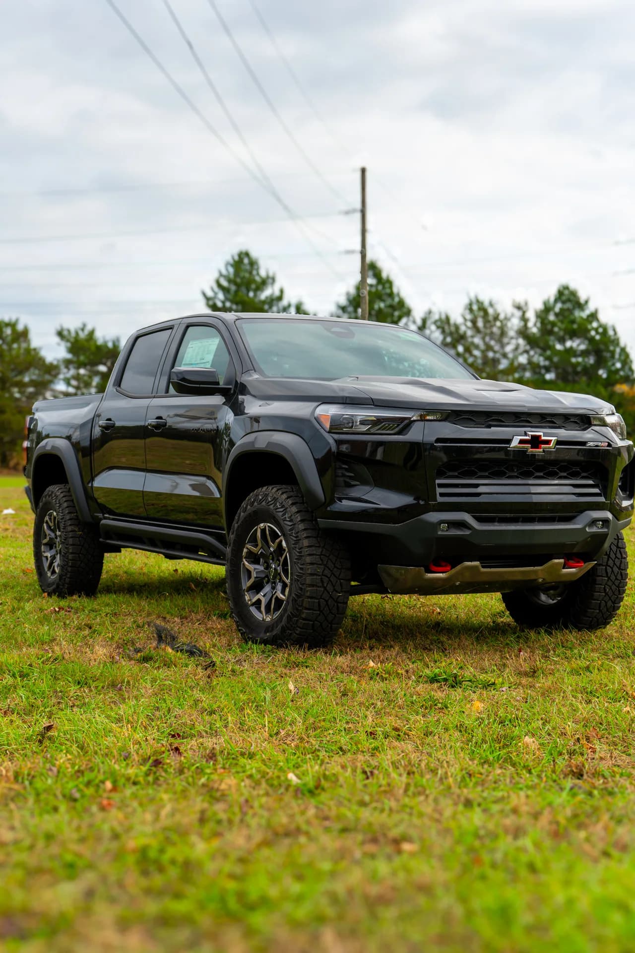 Black Chevrolet pickup photographed from the front on a grassy lot
