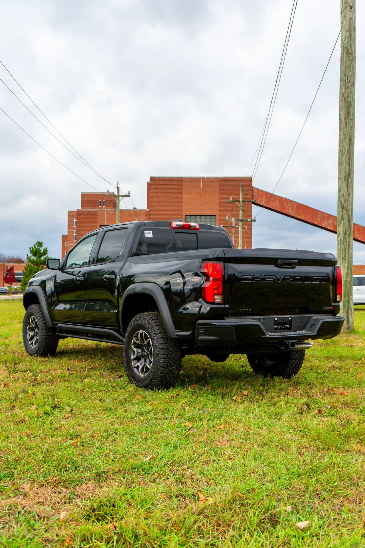 Black Chevrolet pickup photographed from the rear beside a brick building