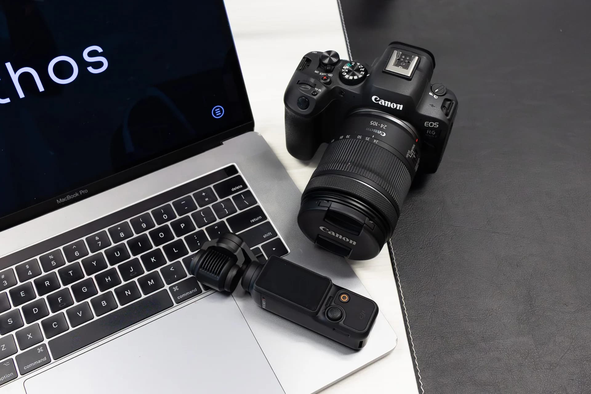 Canon camera and handheld video camera beside an Ethos-branded laptop